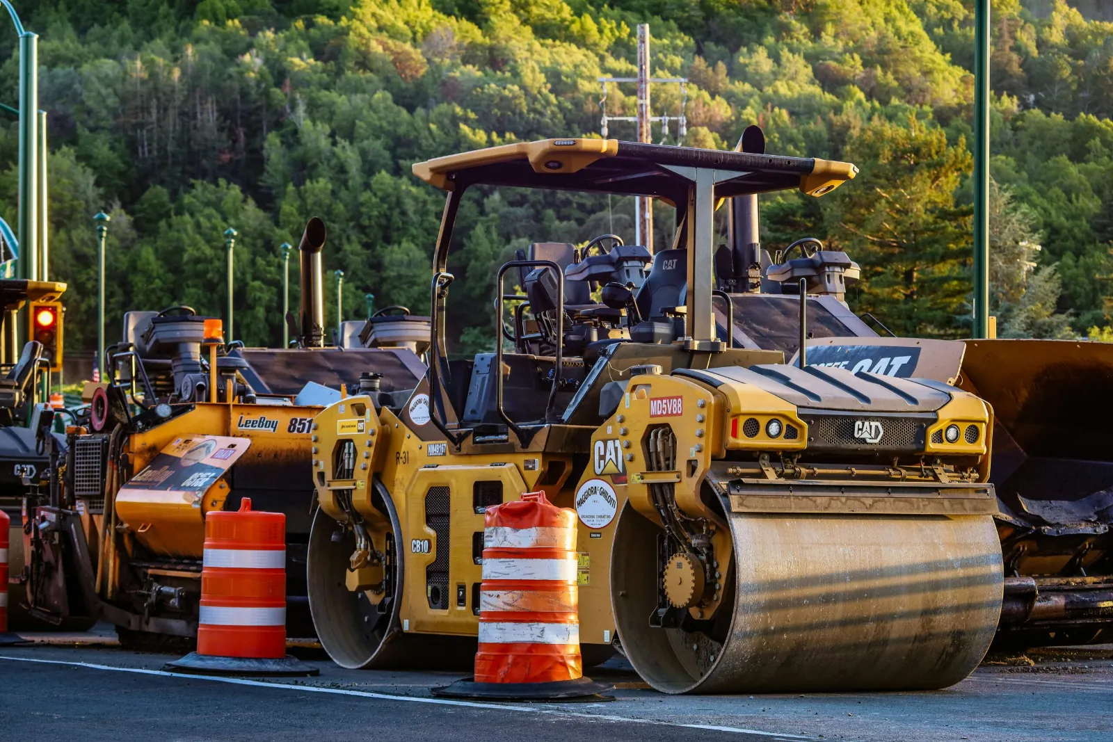 Asphalt roller compacting new pavement beside orange traffic barrels - Wedgewood-Houston asphalt contractor