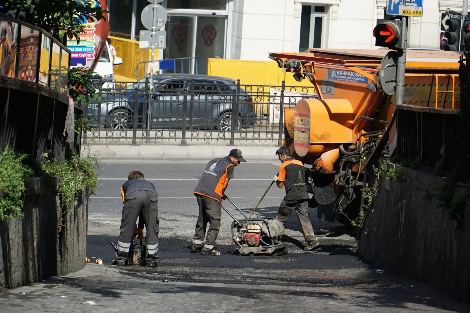 Paving crew working with an asphalt paver on a busy city street